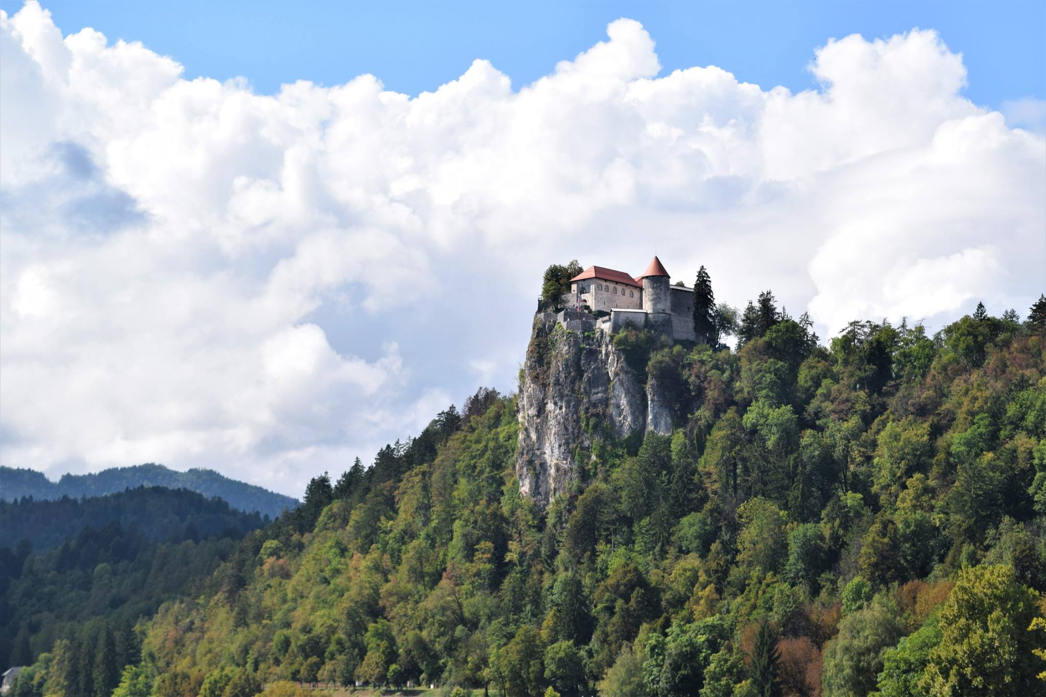 Castle Bled above a forested hillside beneath an open sky.