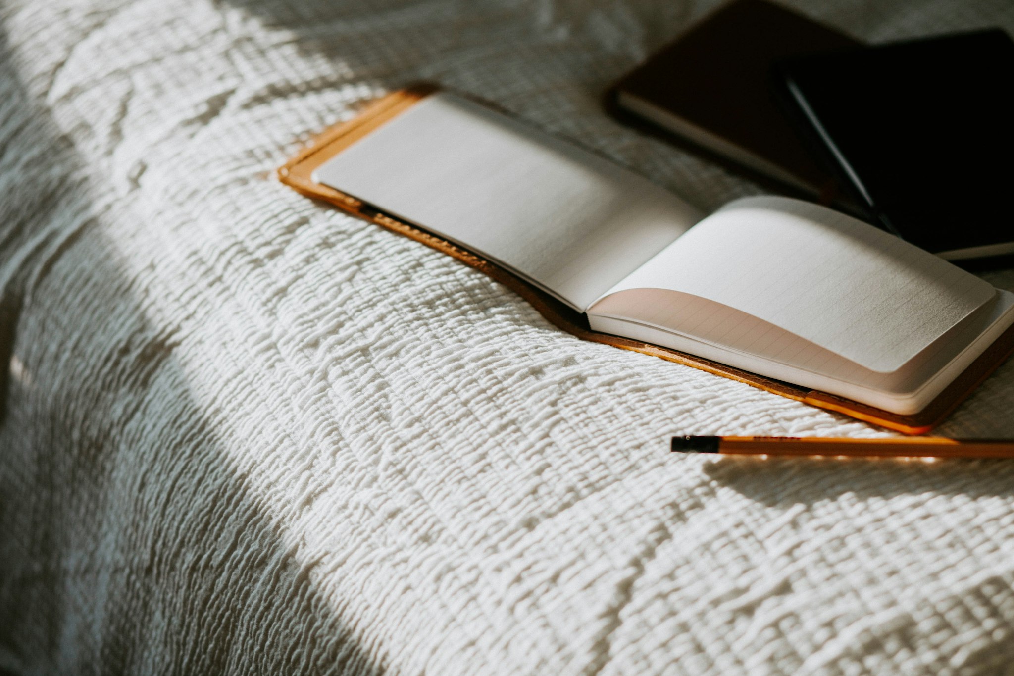 An open notebook and pencil on textured fabric.